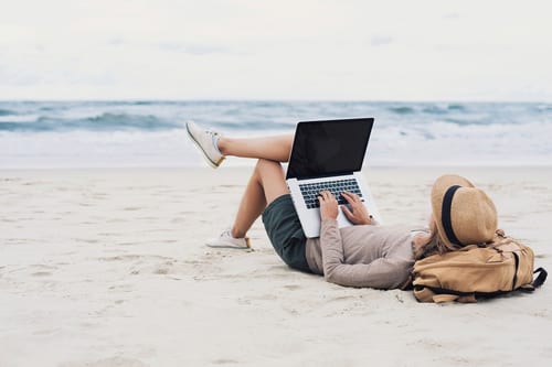 woman working from laptop on the beach